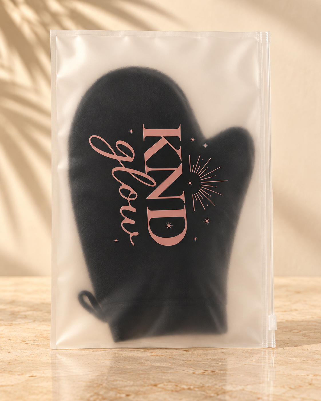 Kind Glow black cosmetic pouch inside a transparent zip bag displayed on a beige surface.